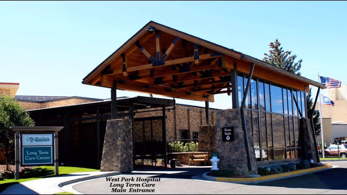 Stone and glass entrance with a wooden peaked awning to a long-term care center.