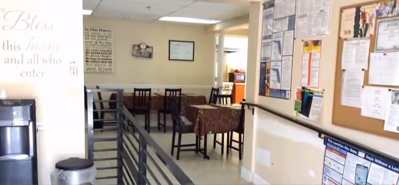 Interior dining room with tables, chairs, bulletin boards, and a railing in foreground.
