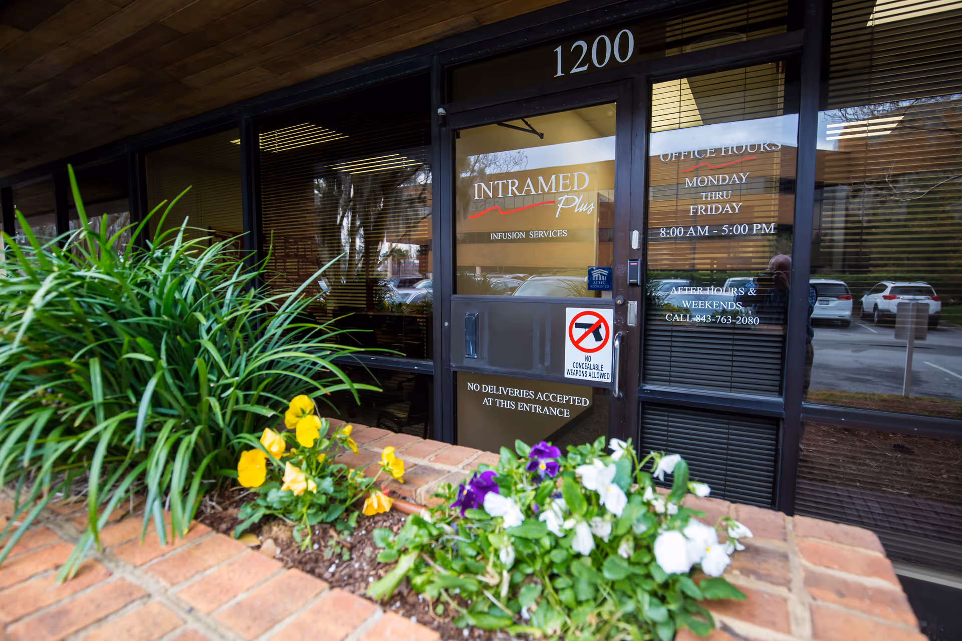 Entrance to Intramed Plus facility with glass doors and colorful flowers.