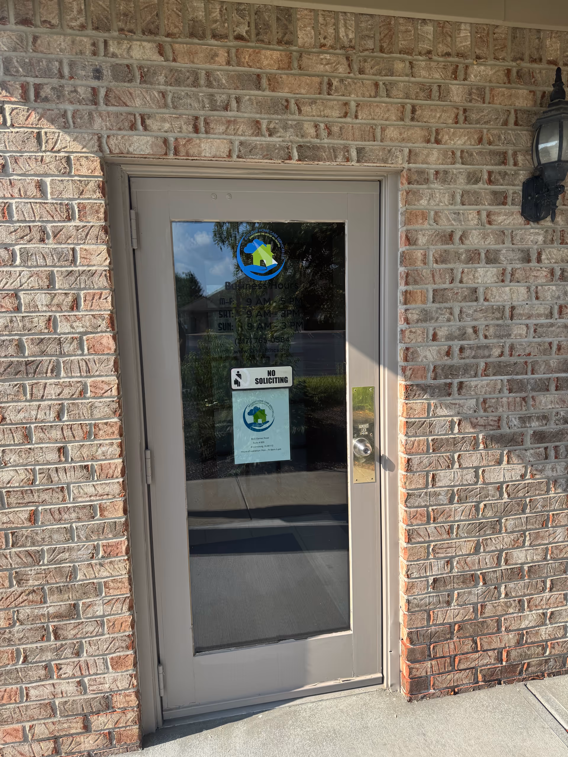 Exterior brick wall with a glass door entrance and signs.