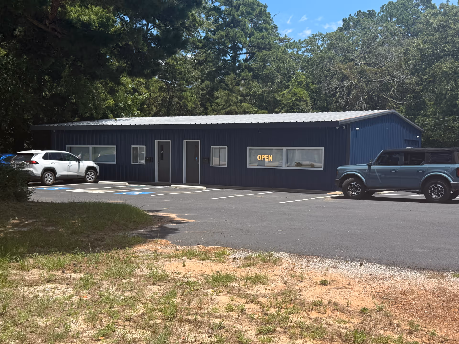 Blue Serenity Pas Therapy facility with open sign, parking lot, and surrounding trees.