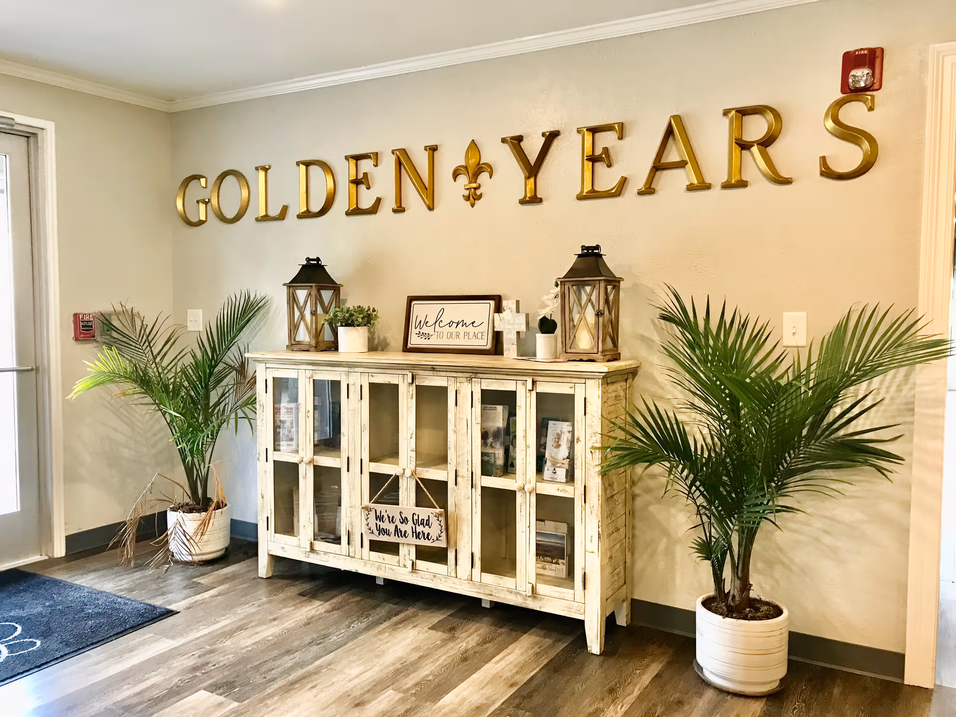Decorated lobby corner with a distressed cabinet, potted palms, lanterns and gold "GOLDEN YEARS" letters on the wall.