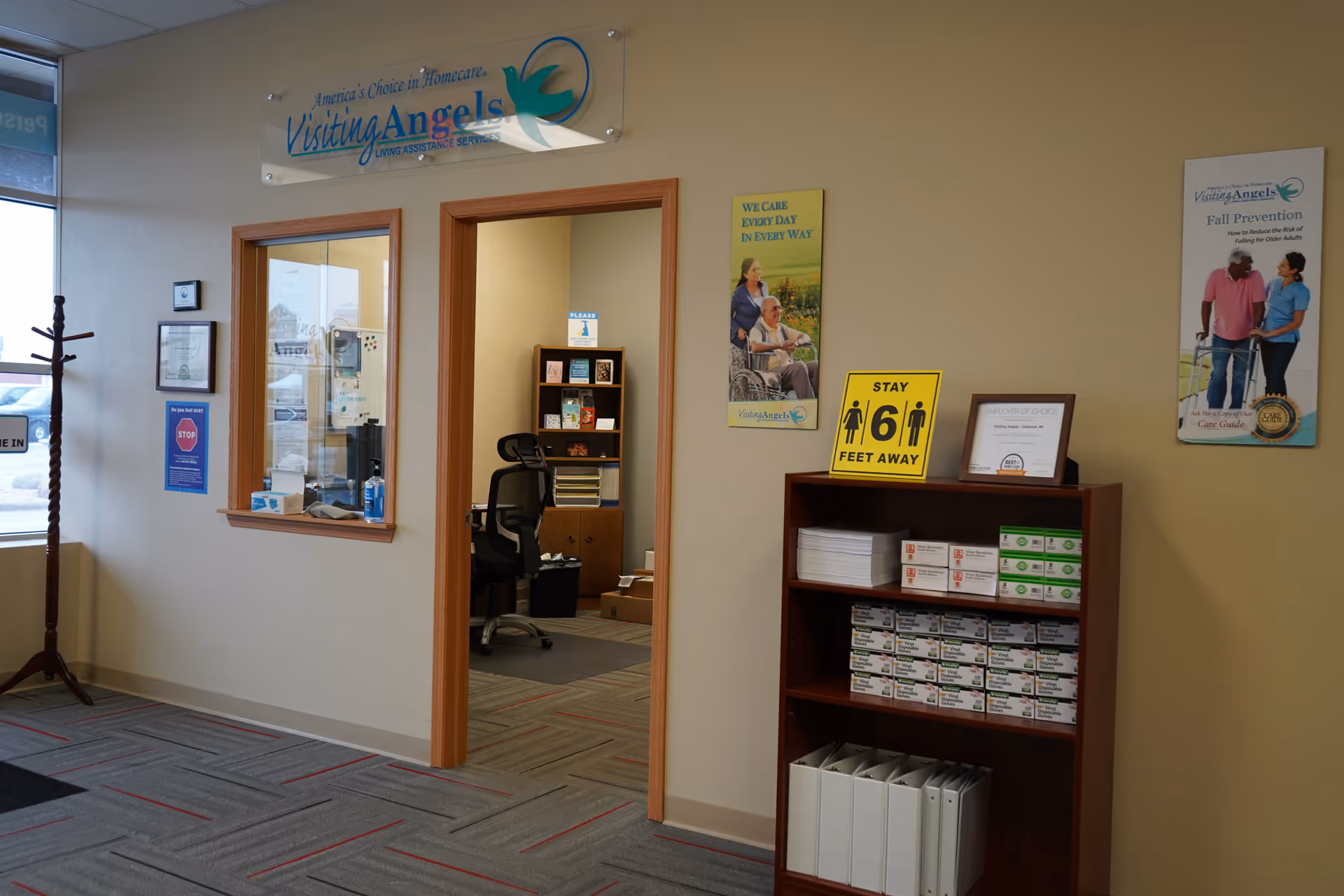 Reception area of Visiting Angels Oshkosh with doorway, signage, posters, and pamphlet shelves.