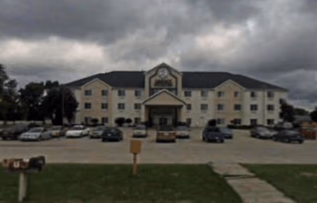 Exterior view of Legacy Estates of Monmouth, a beige senior living facility with a central entrance.