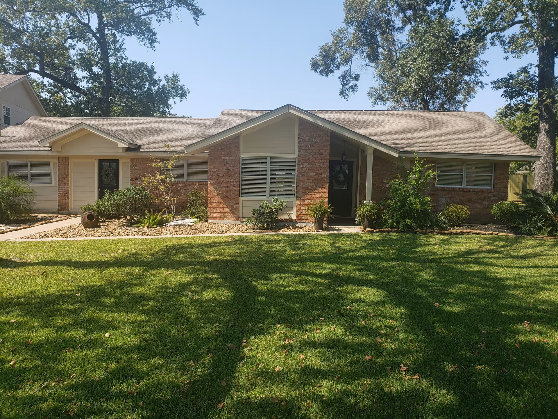 Single-story brick and beige-siding senior living facility front with a green lawn.