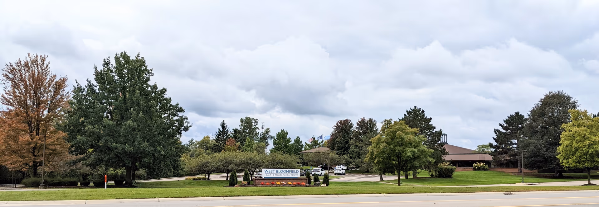 Exterior view of West Bloomfield Nursing Center with trees and a clear sky.