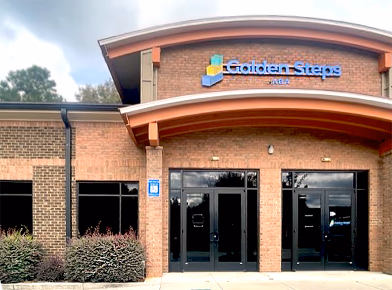 Exterior view of Golden Steps ABA facility entrance with brick facade and glass doors.