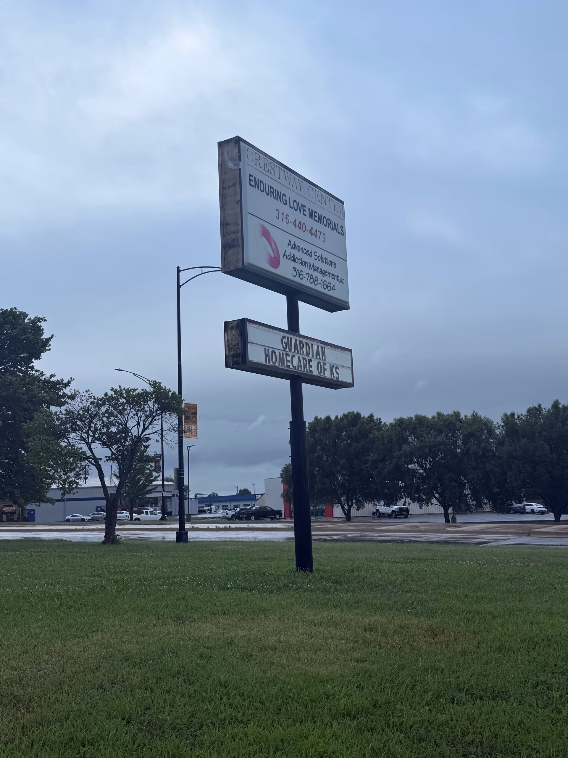 Tall sign for Guardian Home Care of KS on a grassy median beside a road.