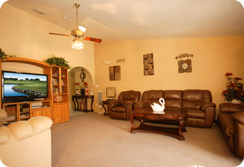Cozy living room with brown leather sofas, a coffee table, and a TV.