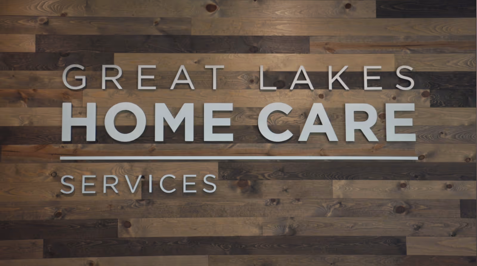 Wood-paneled interior wall with a large Great Lakes Home Care Services sign.