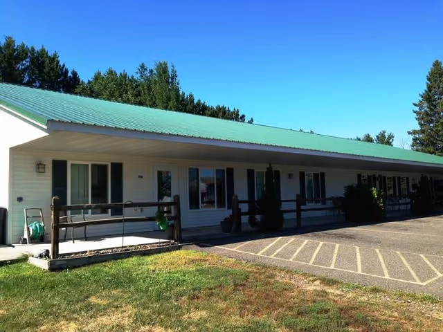 Single-story facility exterior with a green roof and a shaded porch along a parking lot.