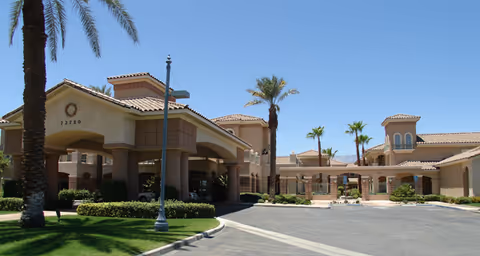 Front view of Brookdale Mirage Inn exterior with drive-through entrance and palm trees.