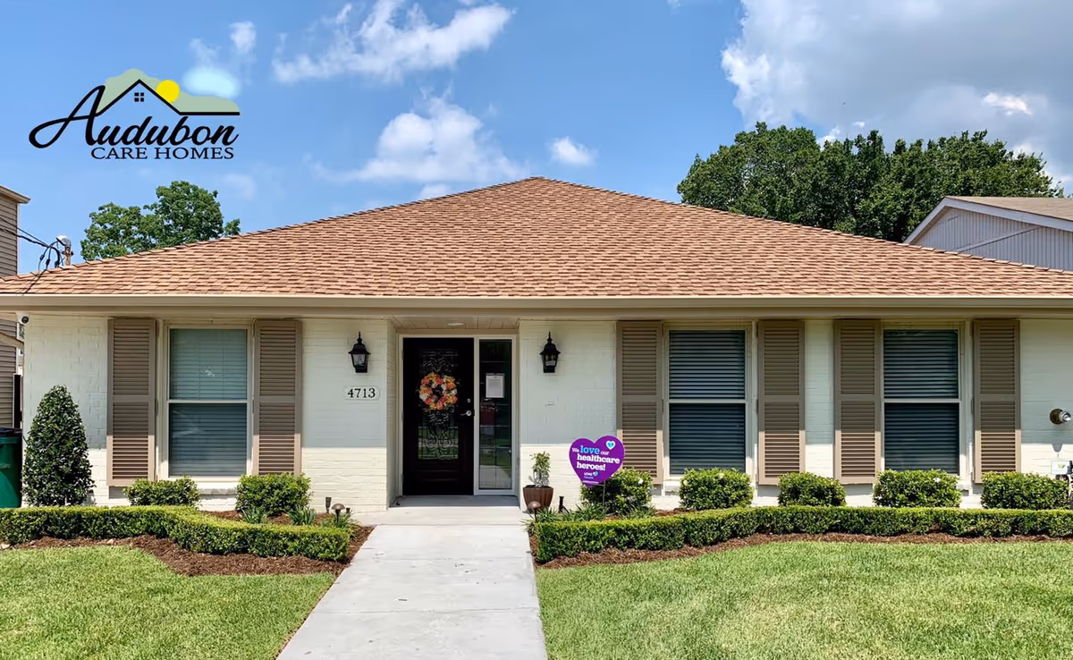 Front view of Audubon Care Homes building with lawn, shrubs, and wreath on door.