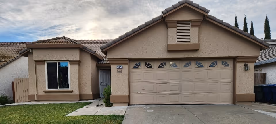 Front exterior of a beige, single-story house with a two-car garage.