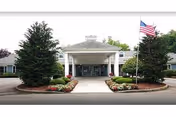 Front entrance of Suffield House senior living facility with a circular driveway and flag