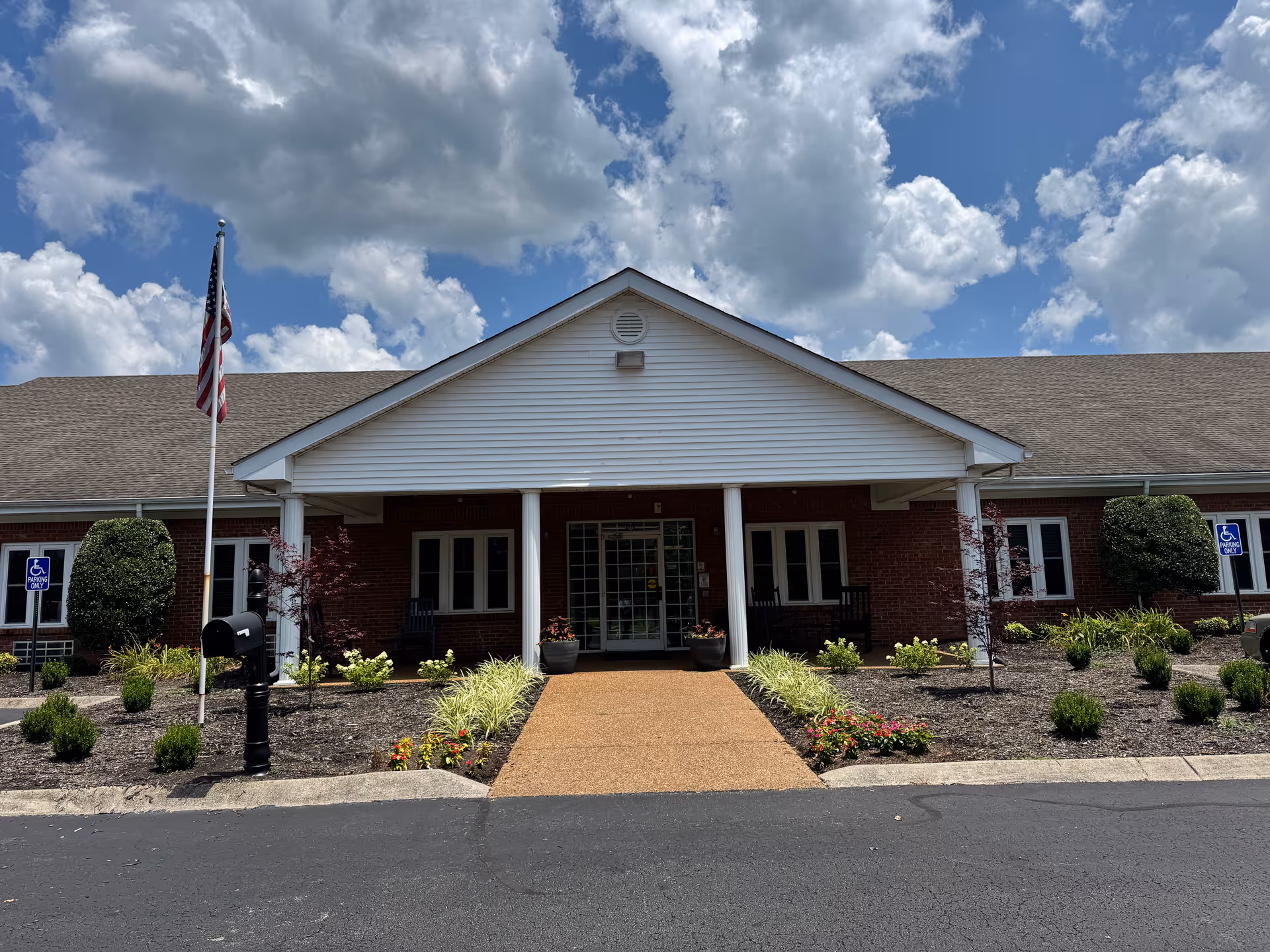 Front view of Stone River Post Acute building with entrance, landscaping, and flag.