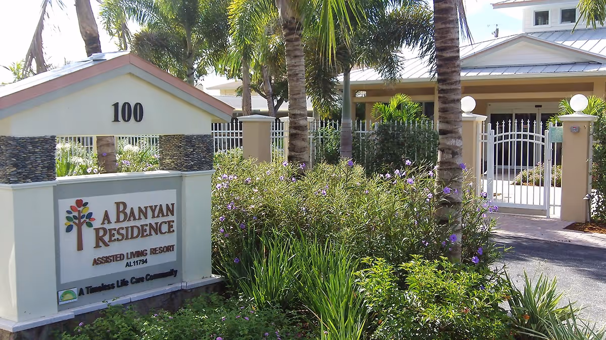 Entrance to A Banyan Residence, gated with a sign, palms, and lush landscaping.