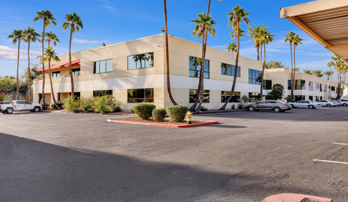 Two-story beige Saudade Chore Services building with palm trees and a parking lot in front.