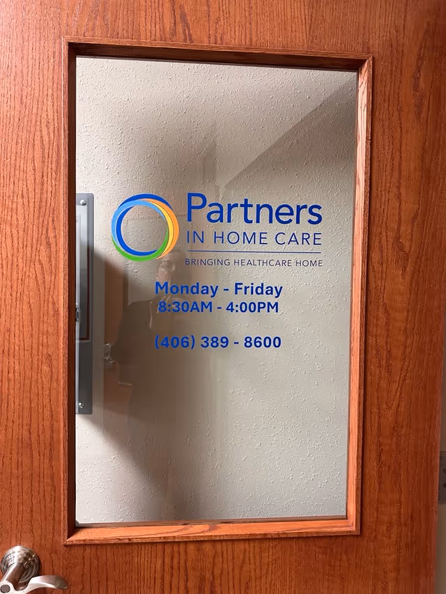 Wood-framed glass door displaying Partners In Home Care Hamilton logo, hours, and phone number.