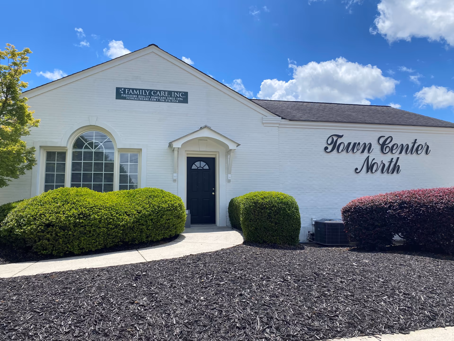 Exterior view of a white senior care building with Town Center North sign and landscaped shrubs.