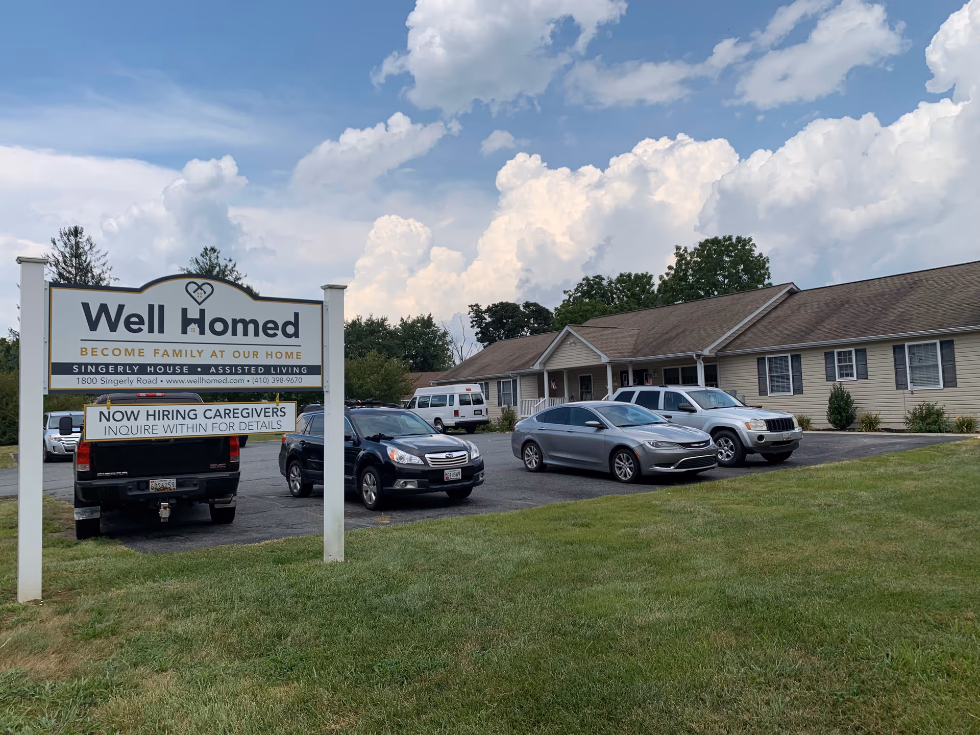 Exterior view of Well Homed Assisted Living with sign and parked cars.