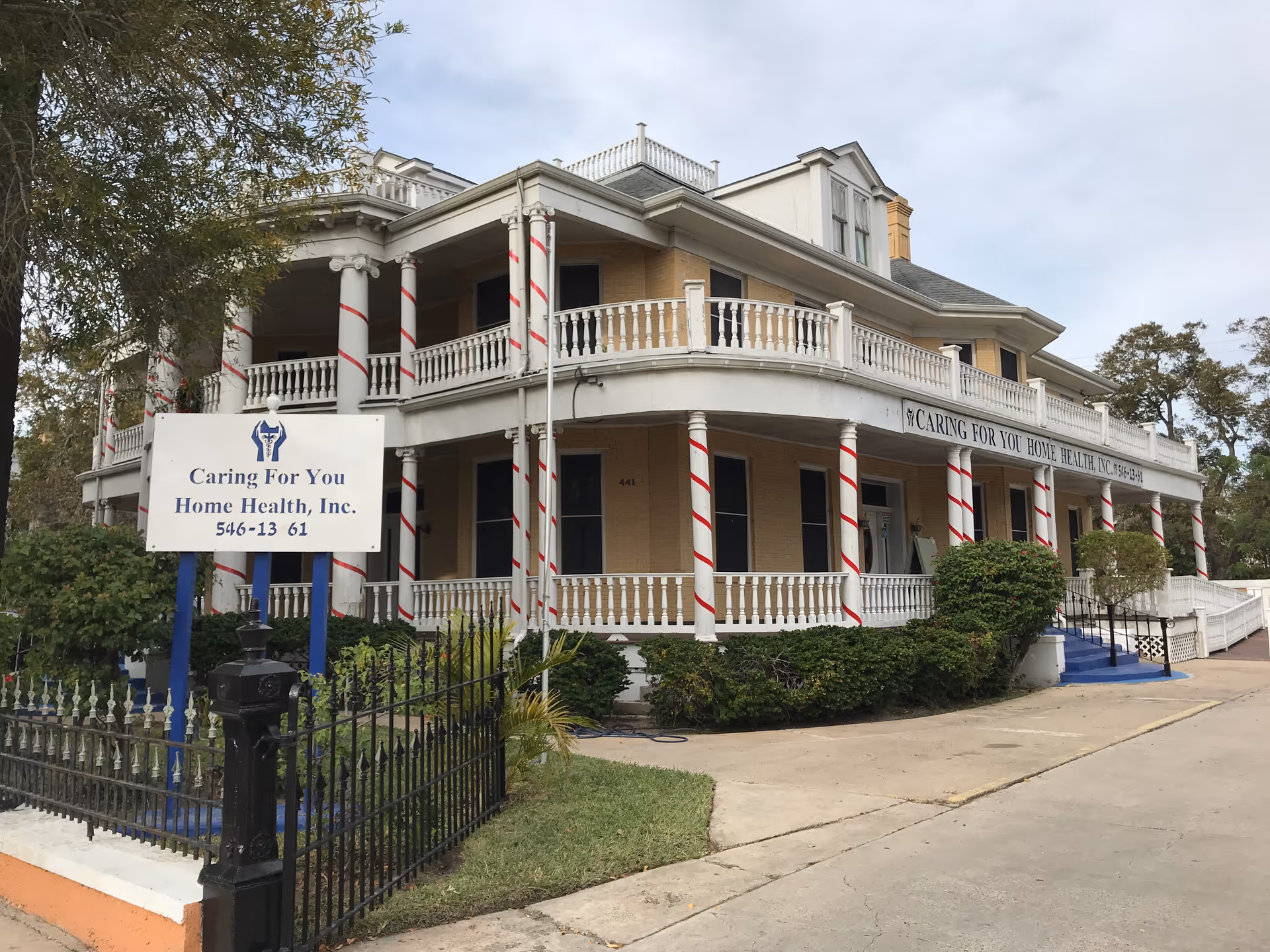 Two-story care facility with wraparound porch and candy-cane striped columns.
