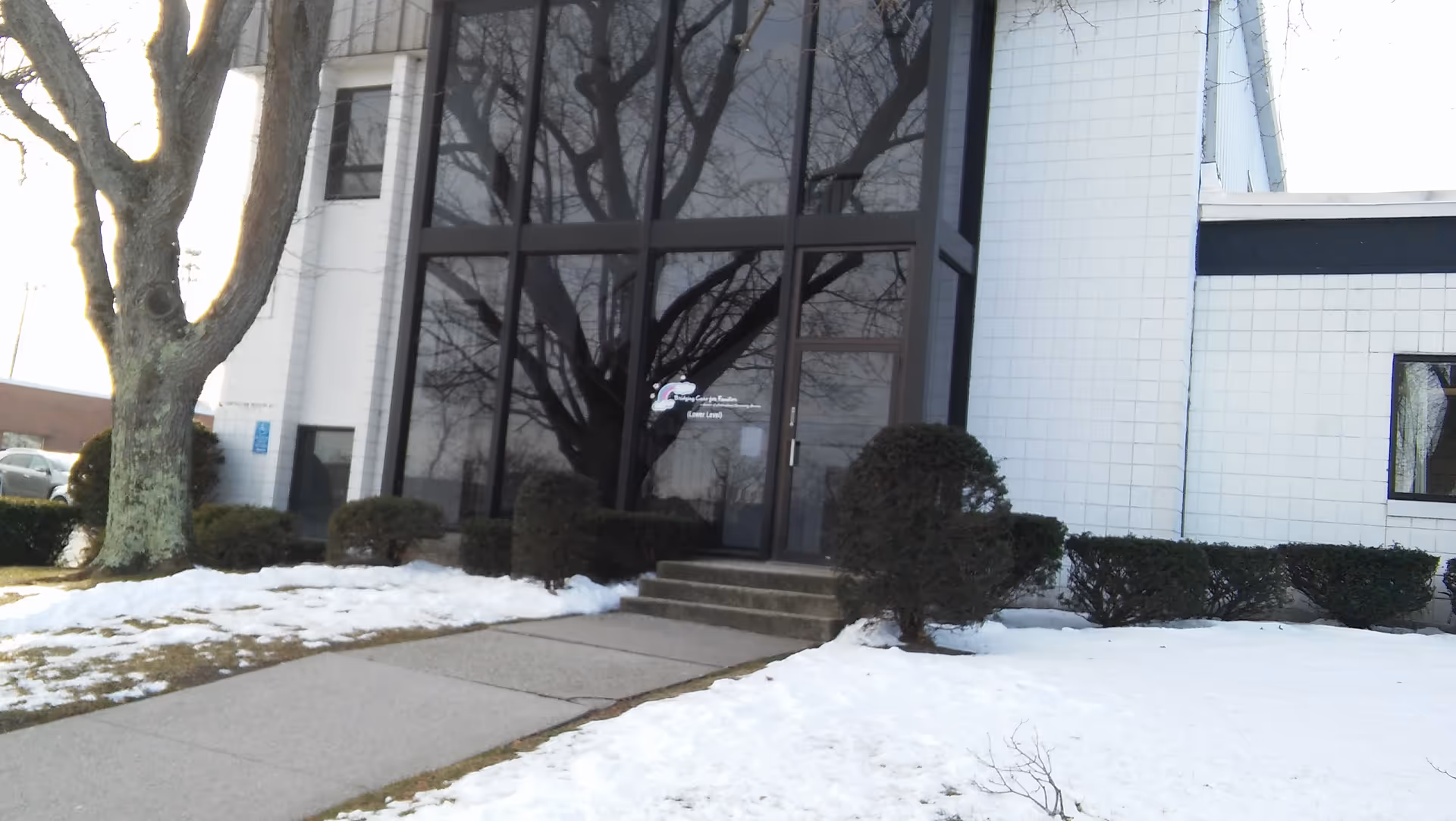 Front entrance of Bridging Care For Families building with glass doors and snowy sidewalk