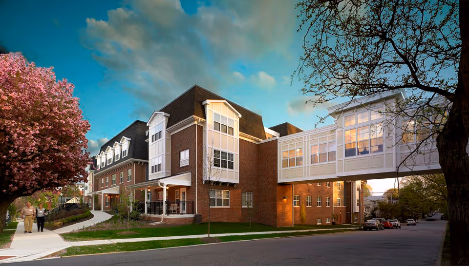 Exterior view of a brick senior living facility with a connecting skybridge.