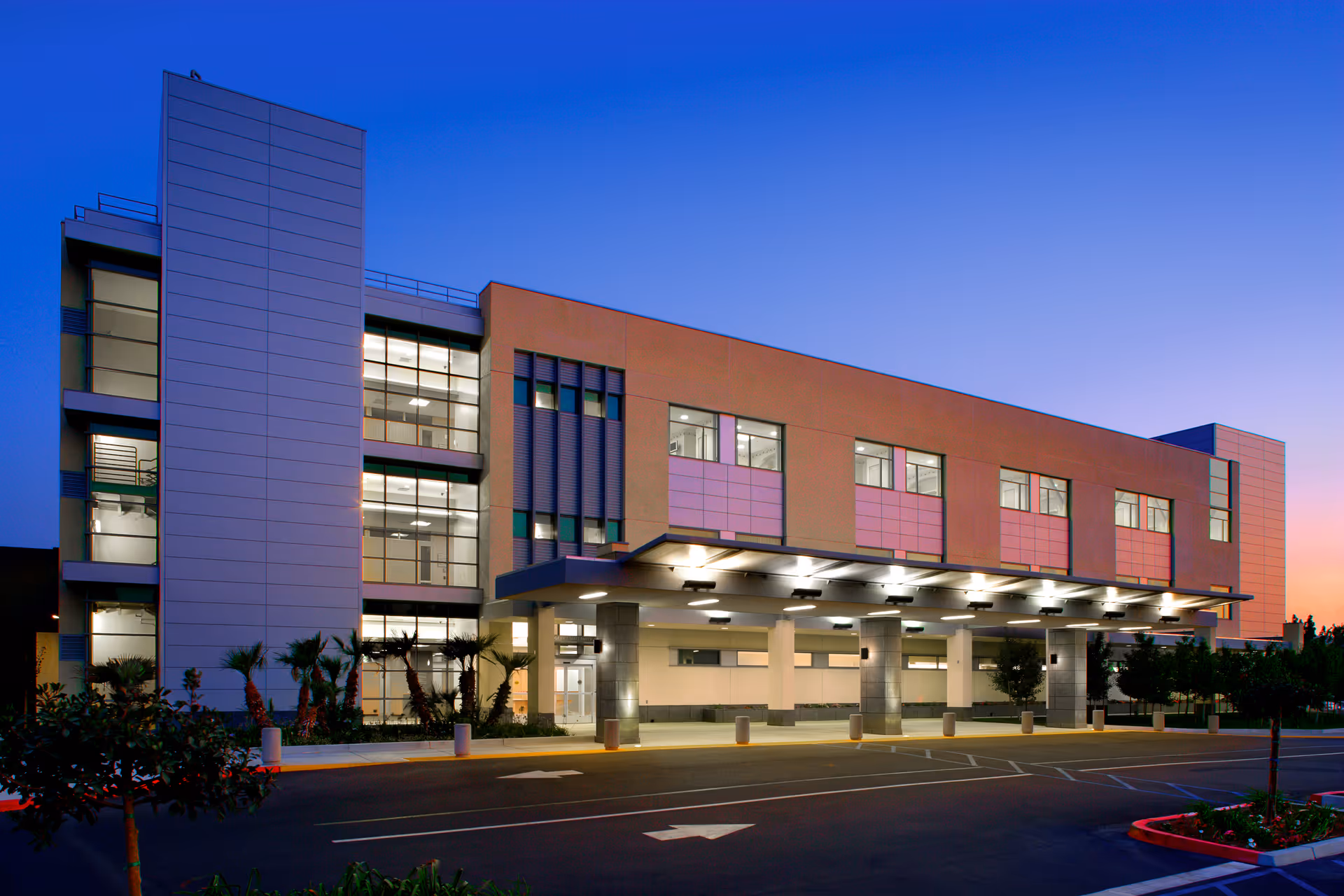 Exterior view of Redlands Community Hospital at dusk with the illuminated entrance canopy.