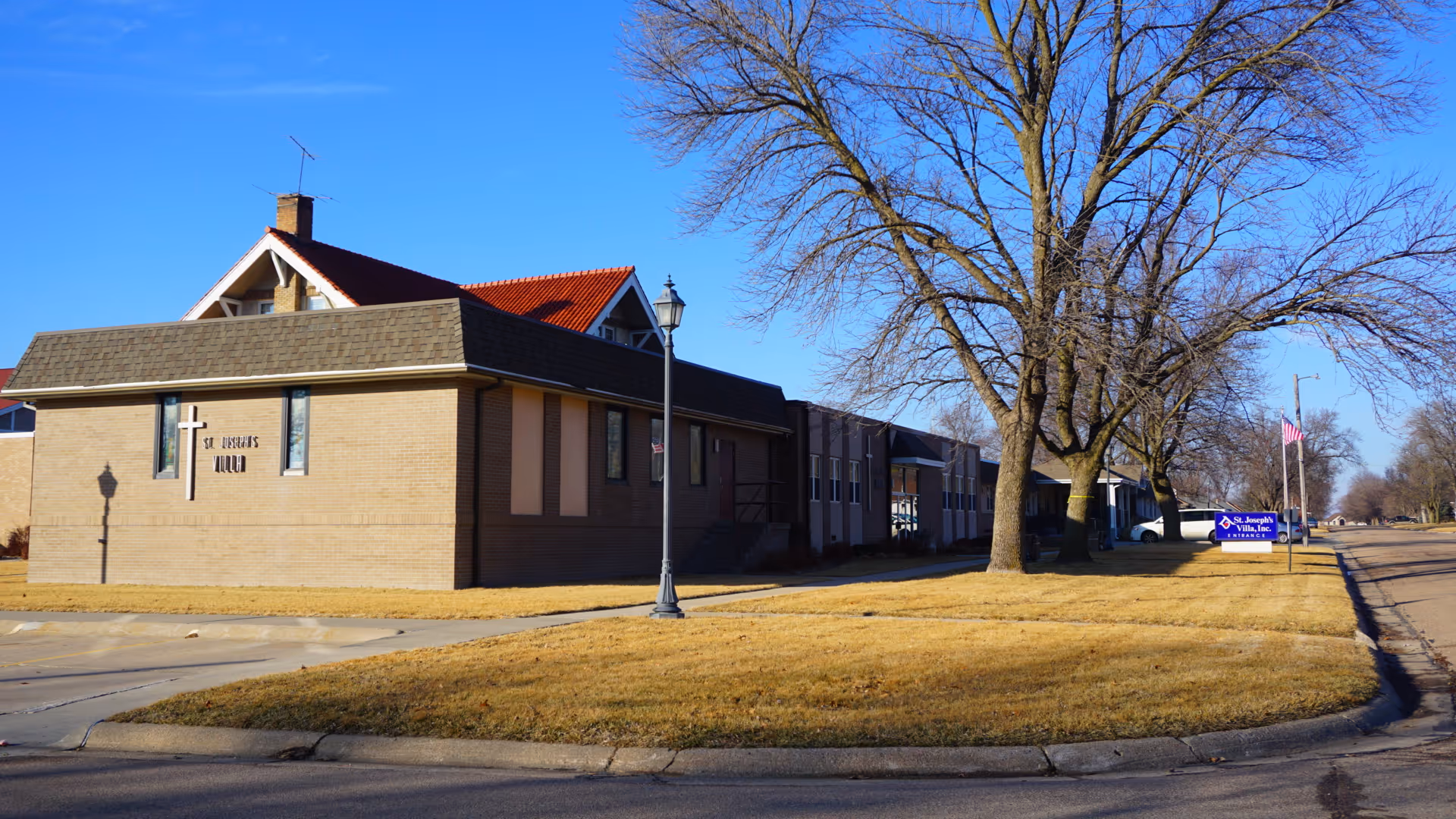 Exterior view of a brick senior living facility with trees and a street