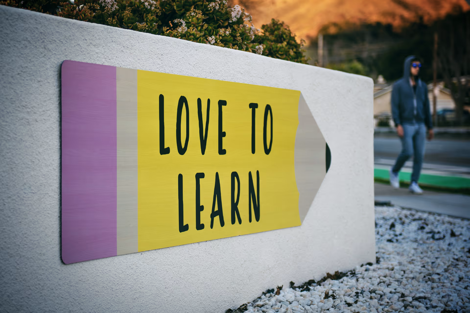 Colorful sign reading LOVE TO LEARN mounted on a white exterior wall.