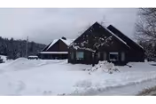 Snow blankets the front of Greensboro Nursing Home, a dark-roofed building under a cloudy sky.