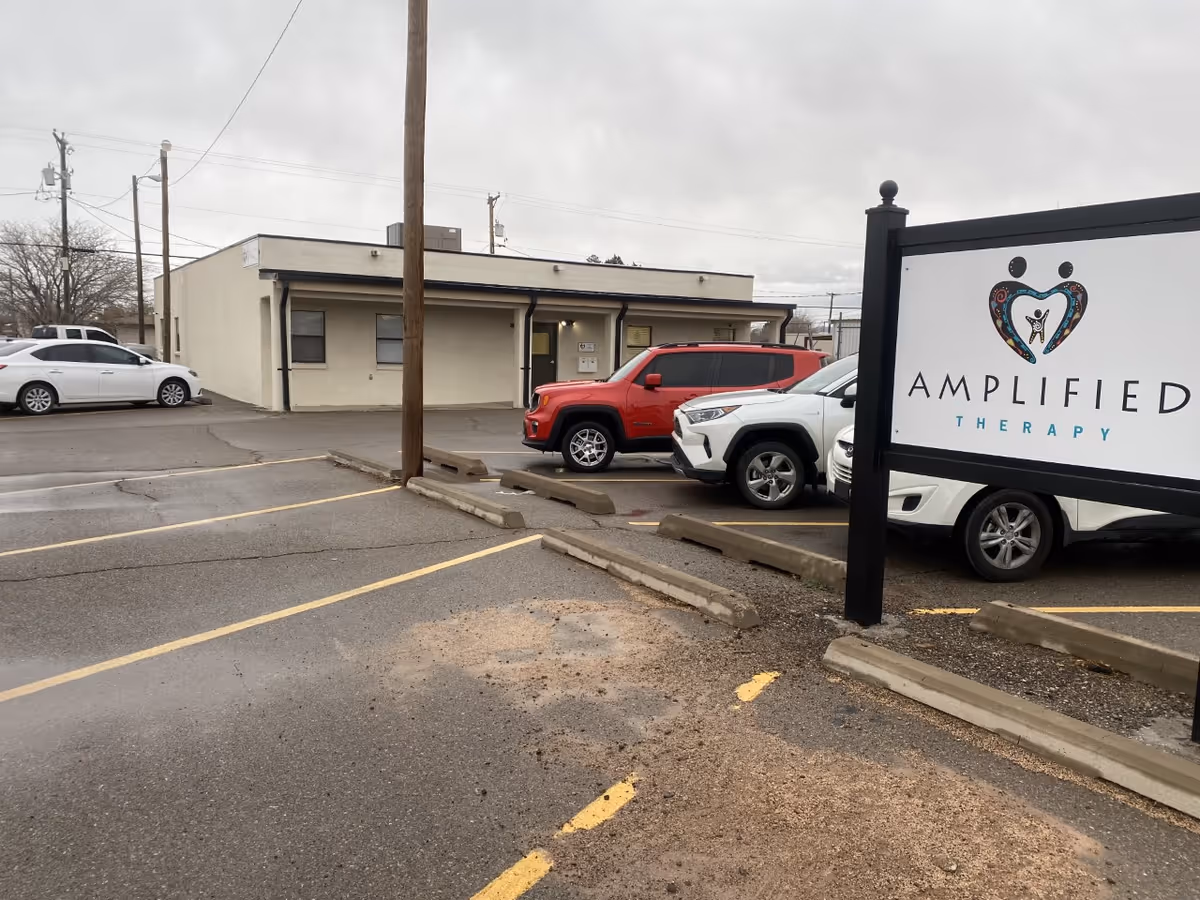 Exterior view of Amplified Therapy facility with parked cars in the front lot.