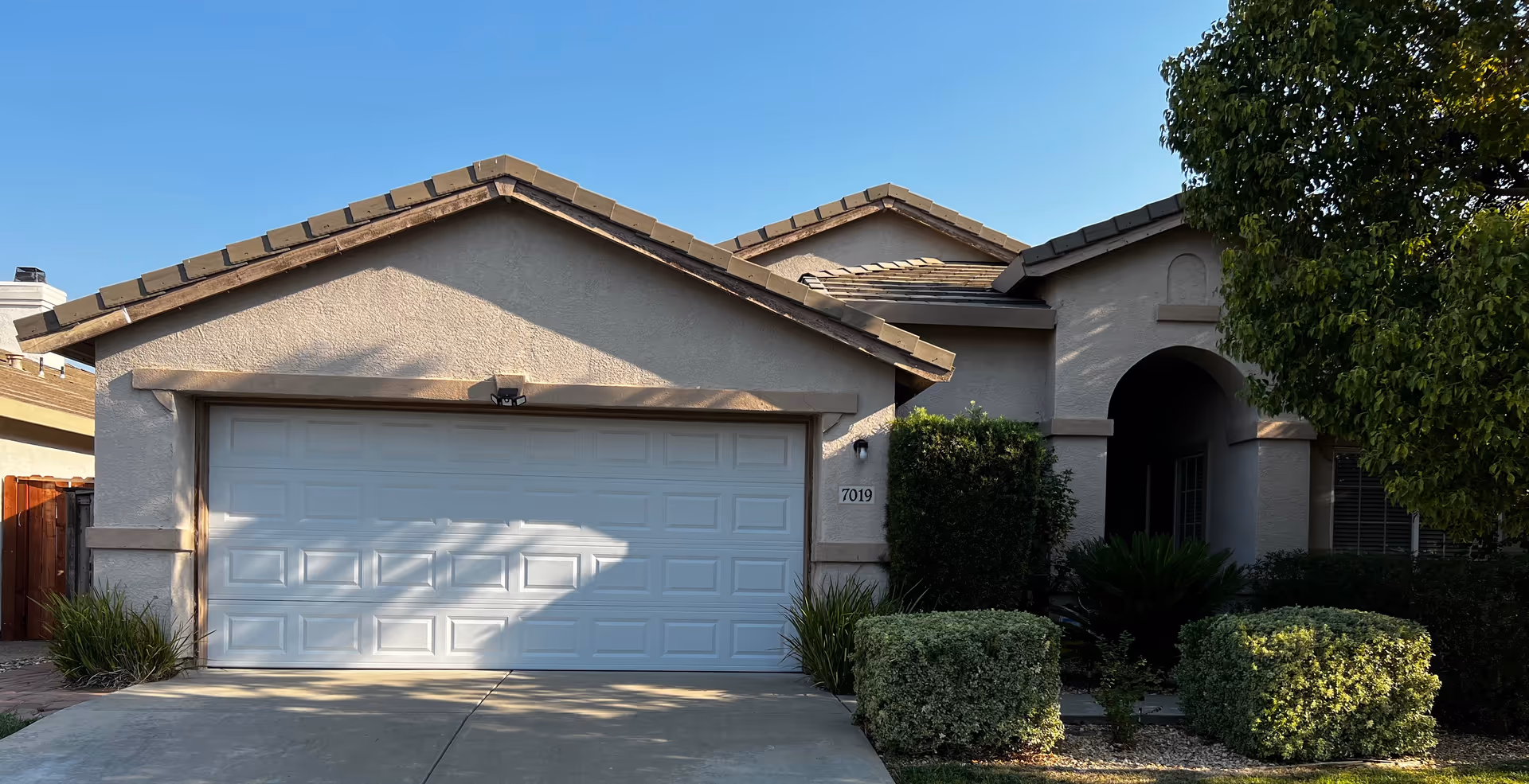 Front view of a beige single-story assisted living home with a two-car garage.