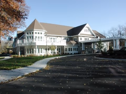 Front view of a two-story senior living facility with balconies and a covered entrance.