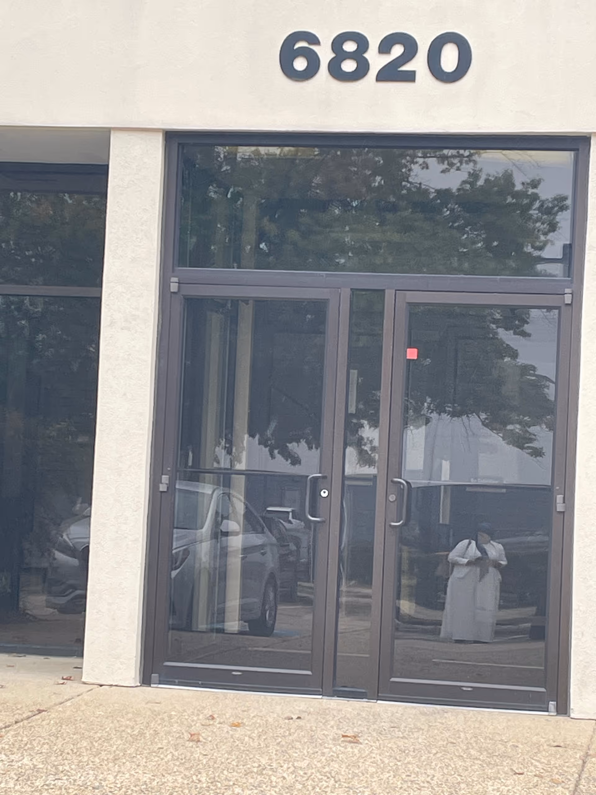 Front entrance with glass doors and the number 6820 on a beige building.