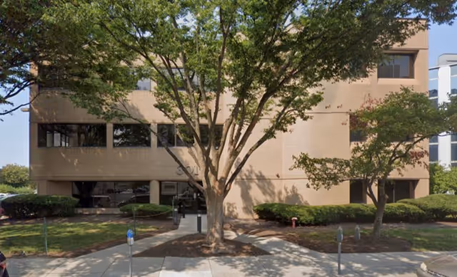 Exterior view of Serenity & Comfort Home Health Care facility with trees and a sidewalk.