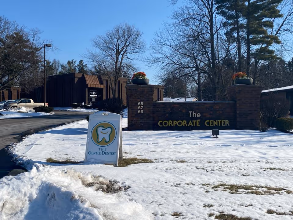 Outdoor brick entrance sign reading The Corporate Center amid snowy landscape.