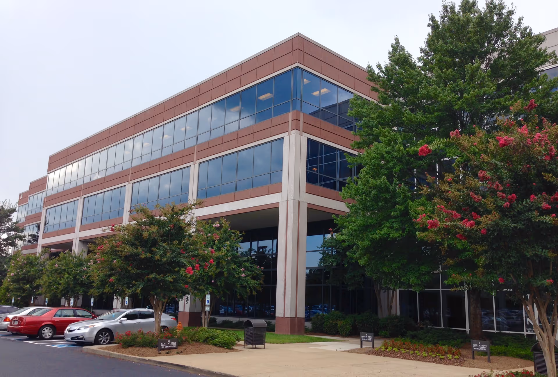 Exterior view of a Compassus facility: a modern glass-front building with surrounding trees and parking lot.
