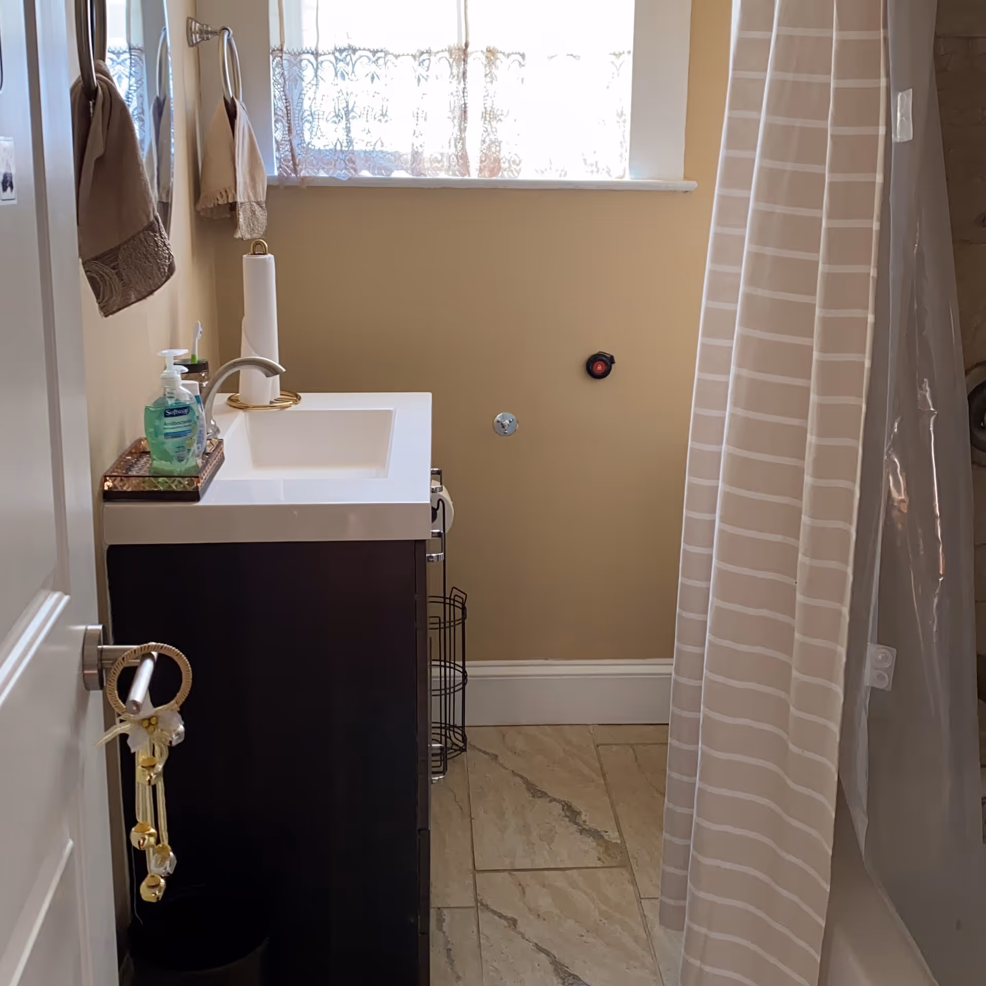 Bathroom in a senior living facility with sink, soap, towels, and striped curtain.