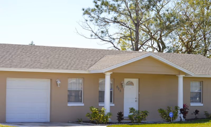 A single-story beige senior living facility with a white garage door and front porch columns.