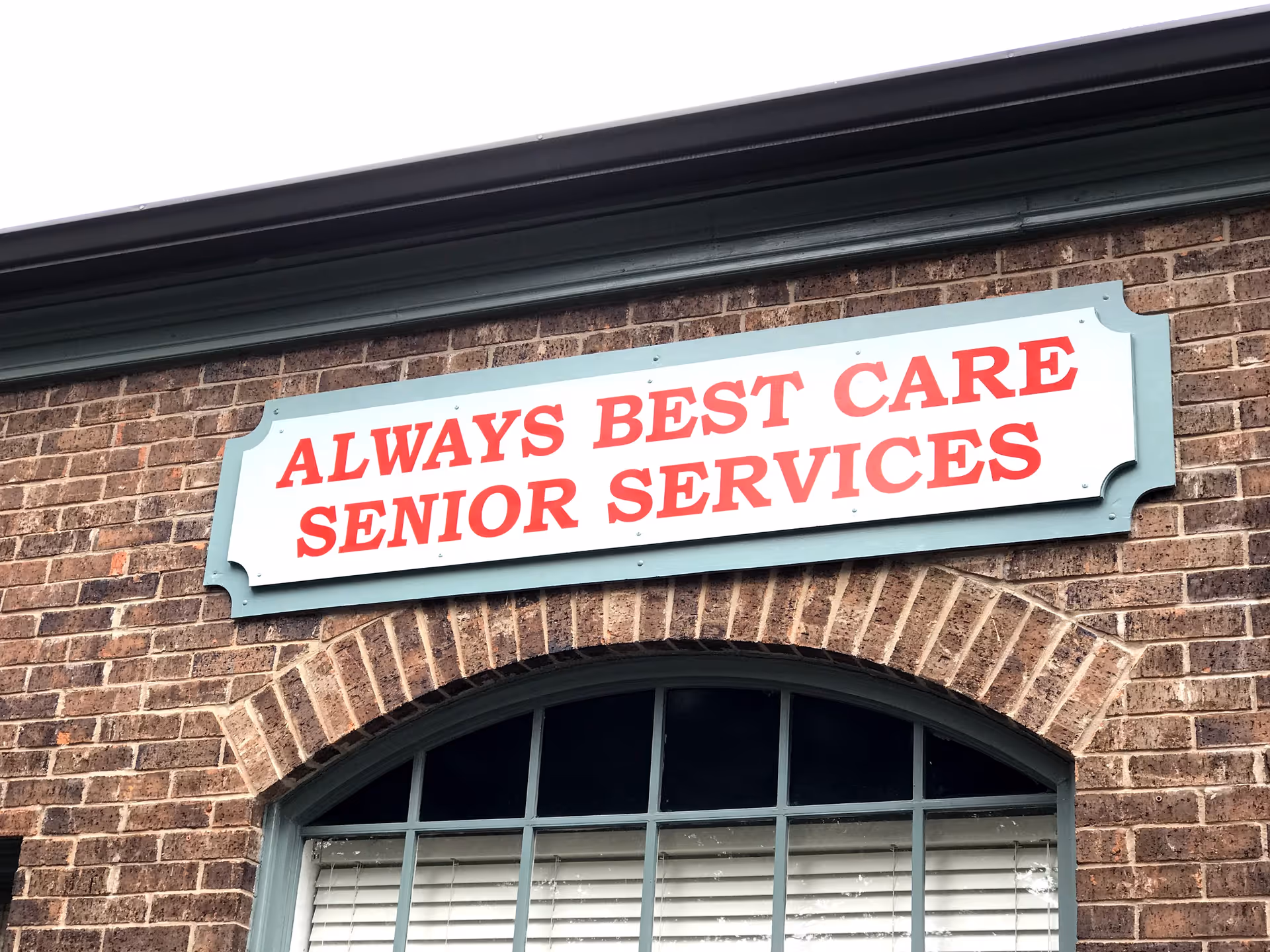 Brick building exterior with arched window and a red sign reading Always Best Care Senior Services.