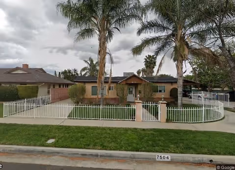 Exterior view of Gateway Homes facility with white fence, palm trees, and front entrance.