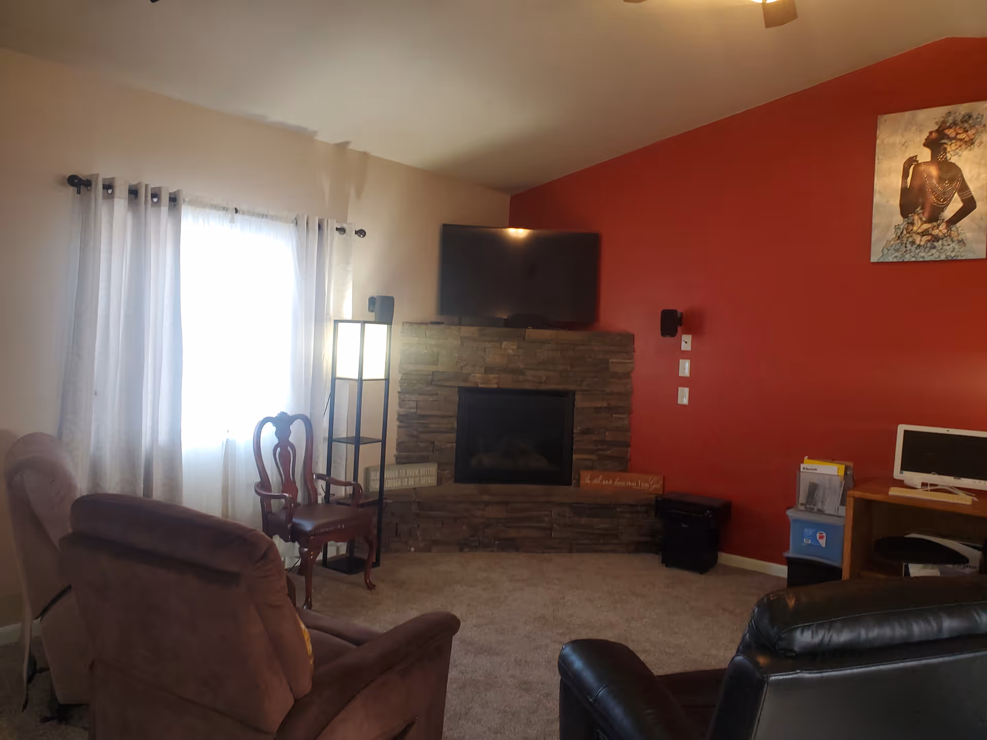 Cozy living room with red accent wall, fireplace, TV, and comfortable seating.