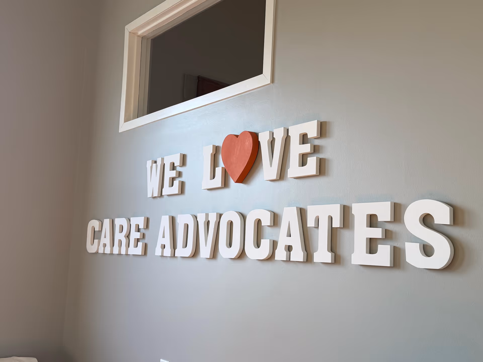 Interior wall displays WE LOVE CARE ADVOCATES sign with a red heart.