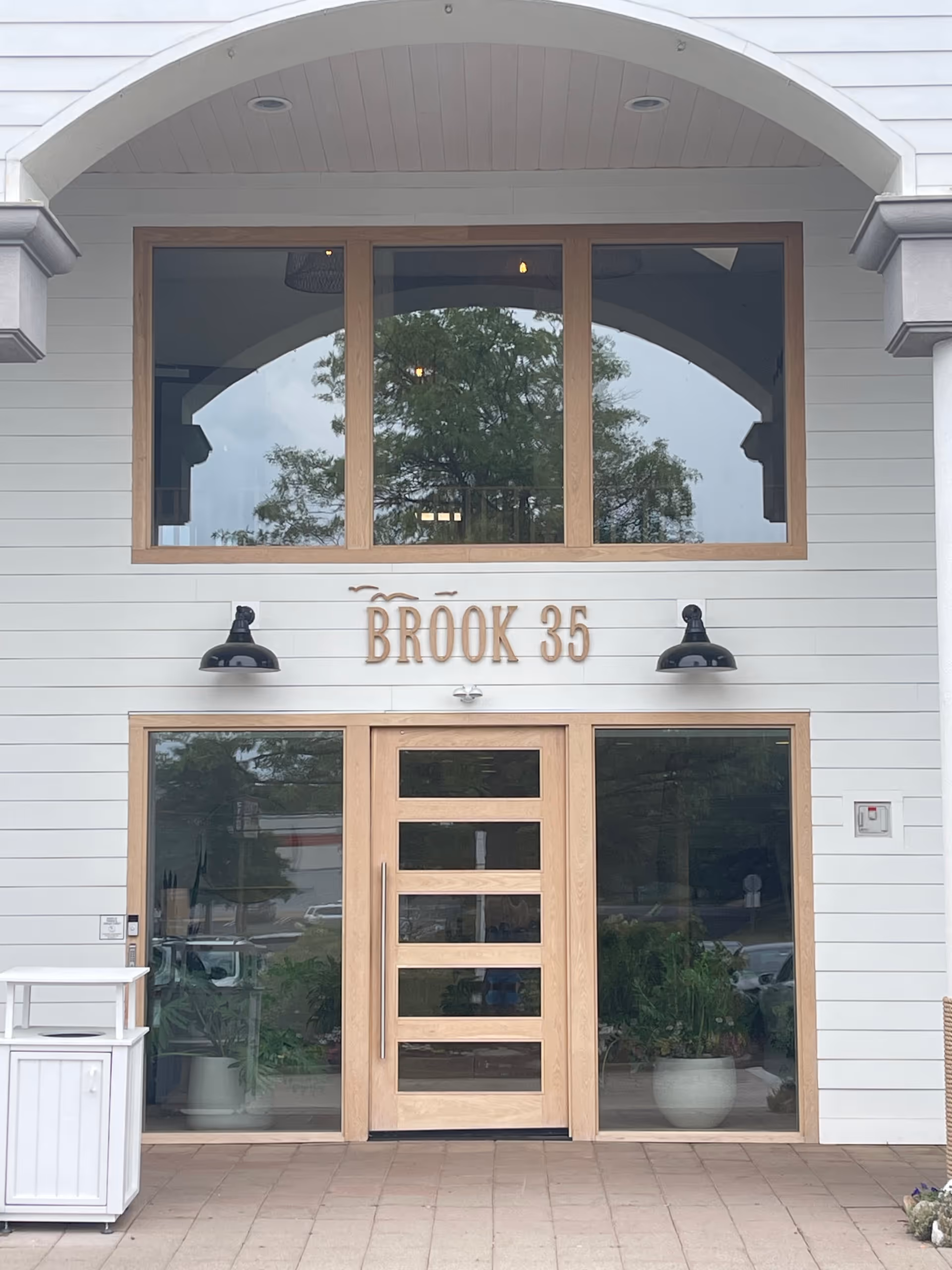 Front entrance of a light-colored building with large glass doors and 'BROOK 35' sign.