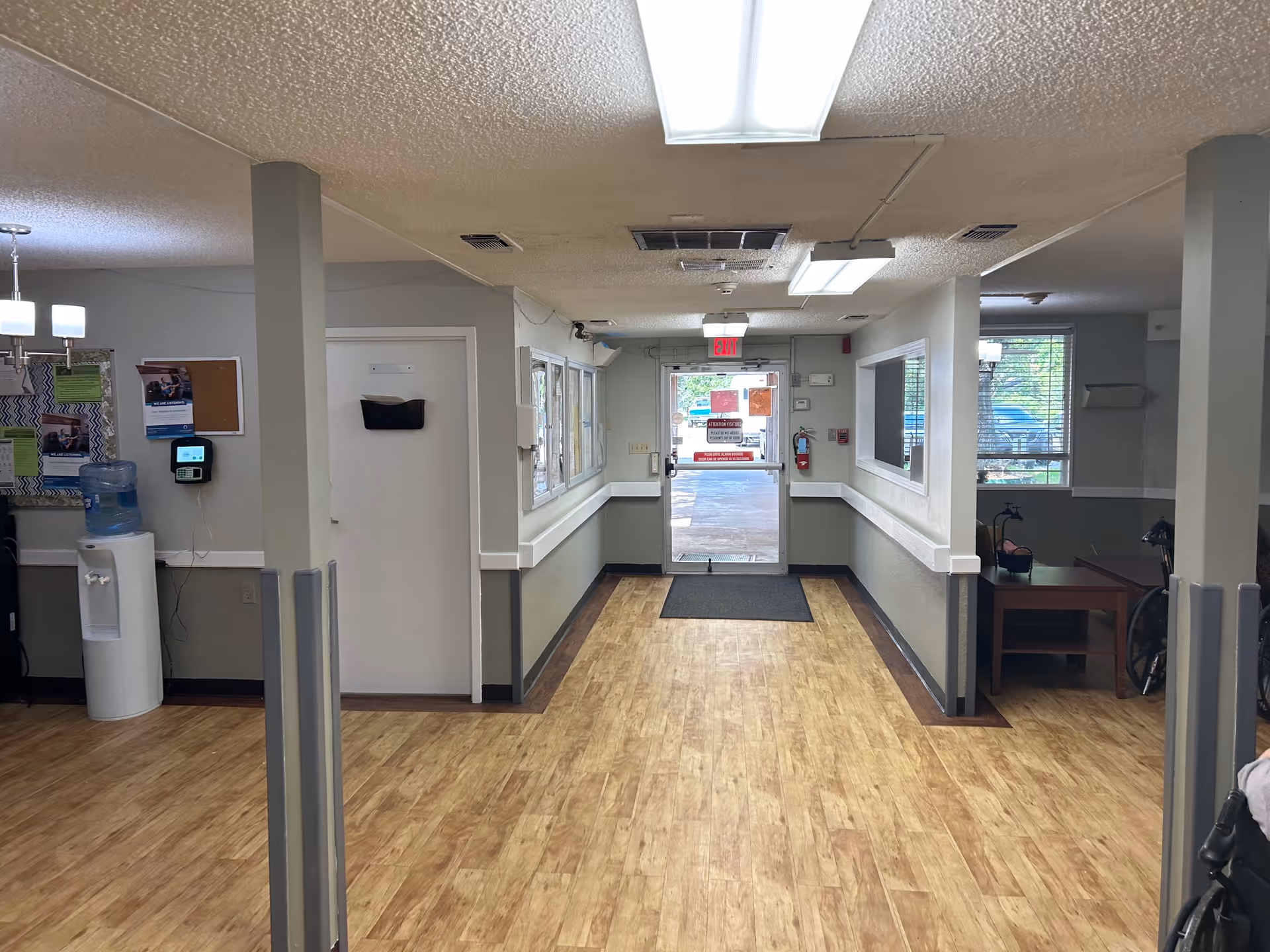 Interior corridor of a senior living facility with wood floors and an entrance door.
