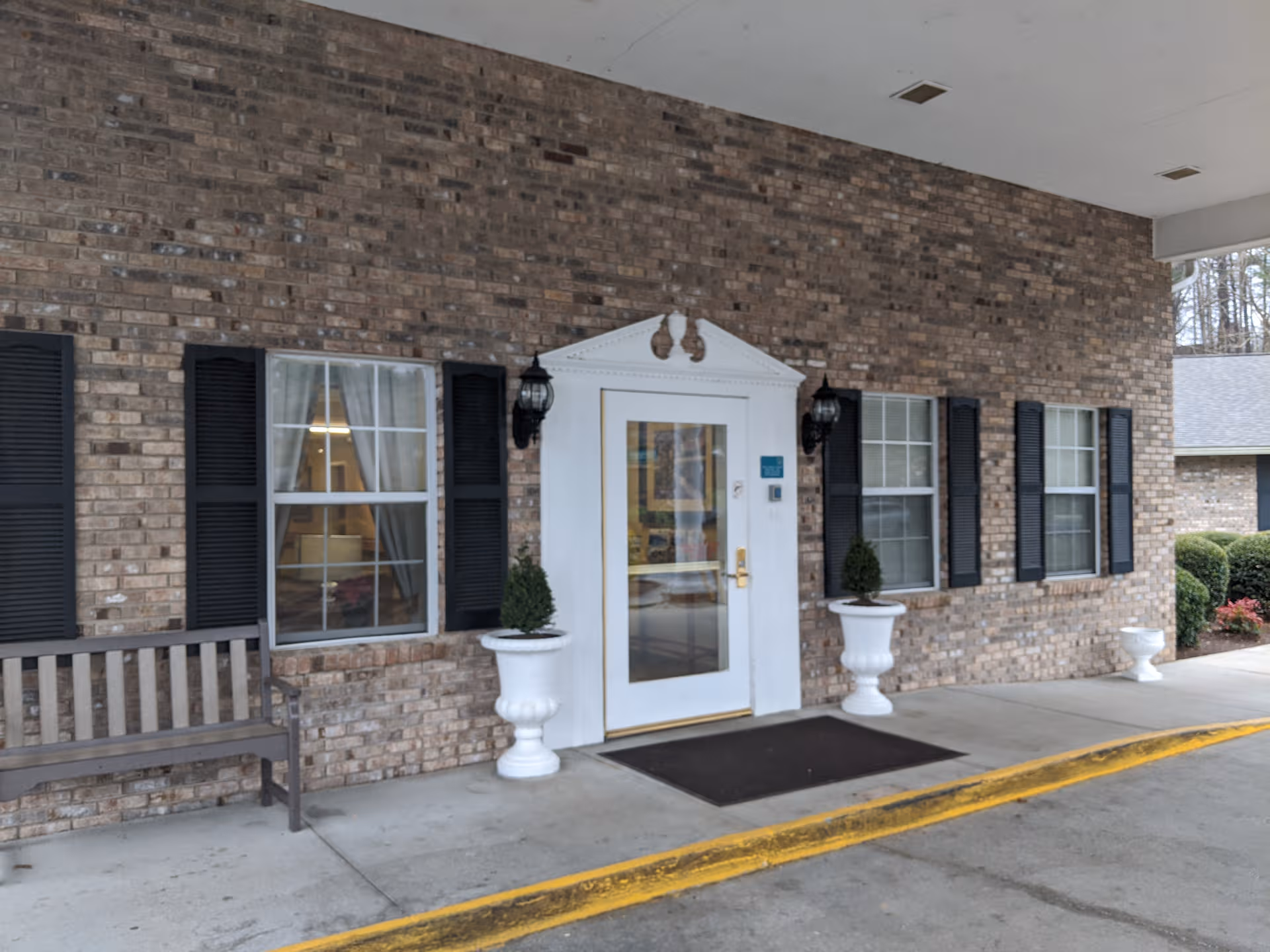 Brick exterior of The Laurels of Hendersonville featuring a white door and black shutters with planters.