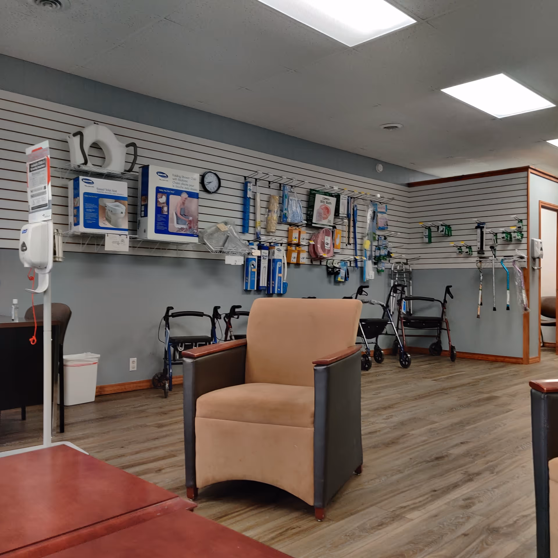 Medical supply wall with devices and a tan armchair in a clinic interior.