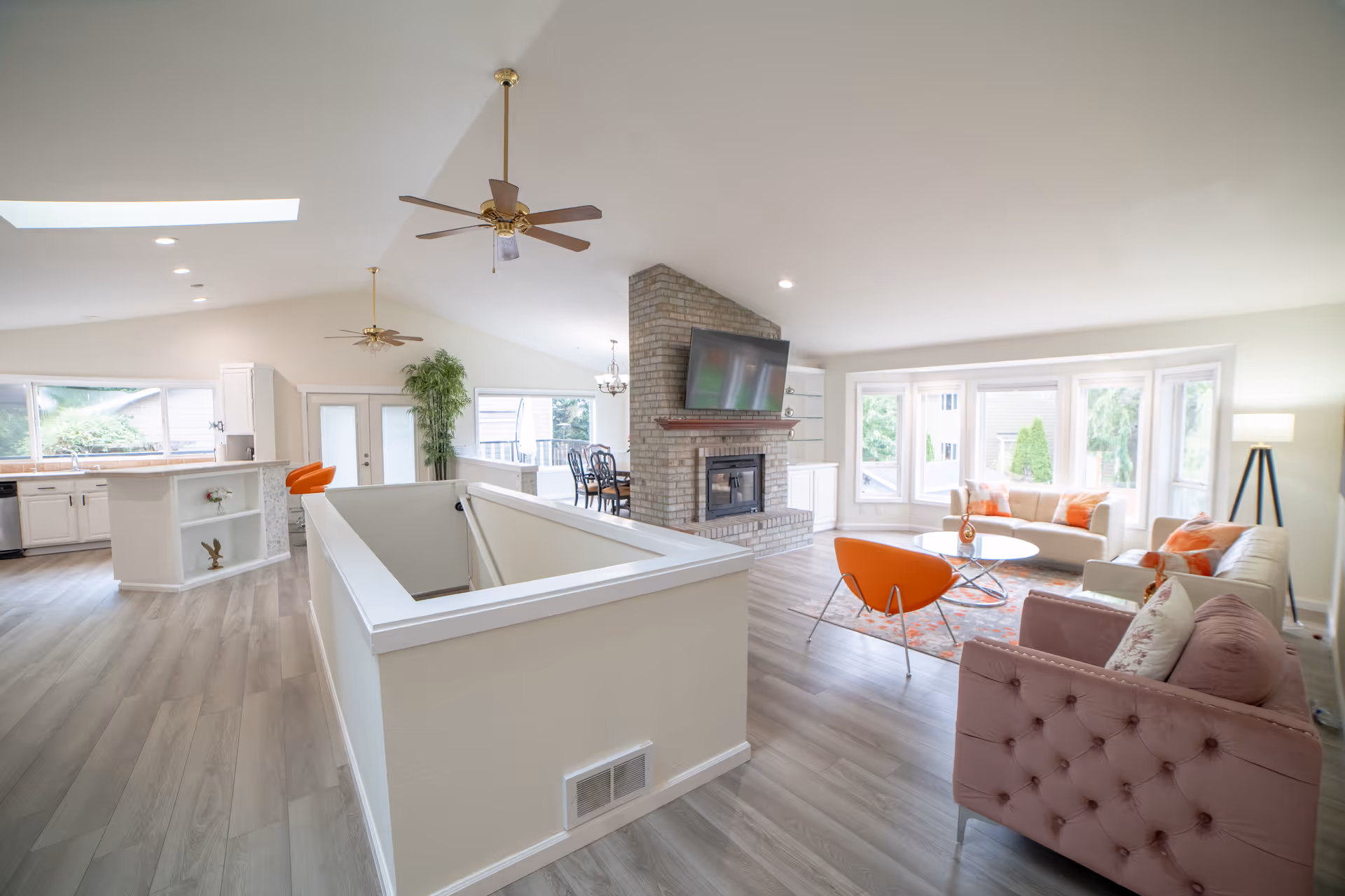 Spacious modern living area with beige and pastel furniture, fireplace, and large windows.